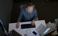 An IT pro at his computer in a dark office
