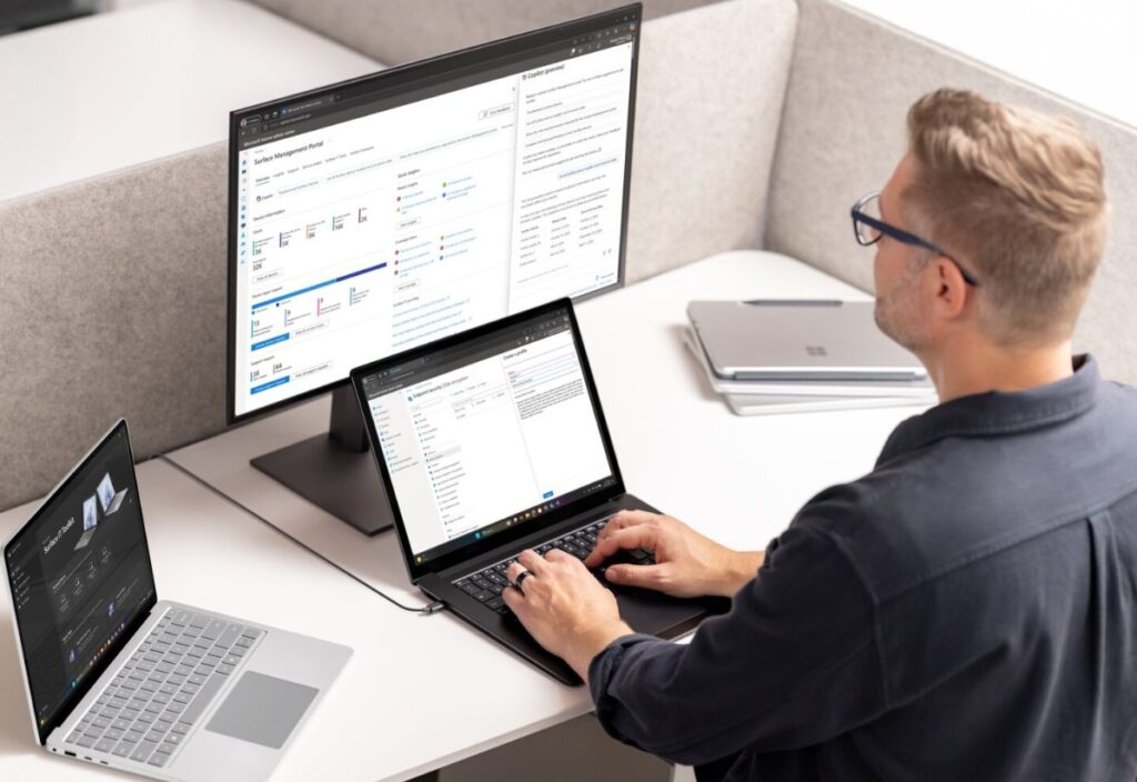 A man sing a Windows 11 PC with a monitor and laptop nearby