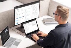 A man sing a Windows 11 PC with a monitor and laptop nearby