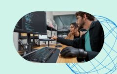 Two people looking at a monitor displaying code