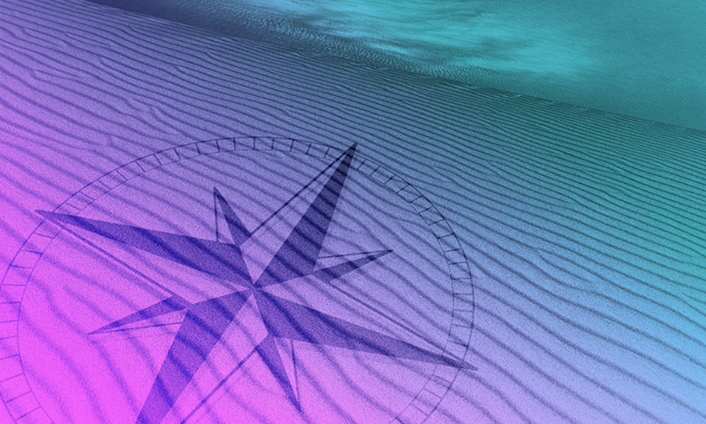 a drawing of a compass on a beach